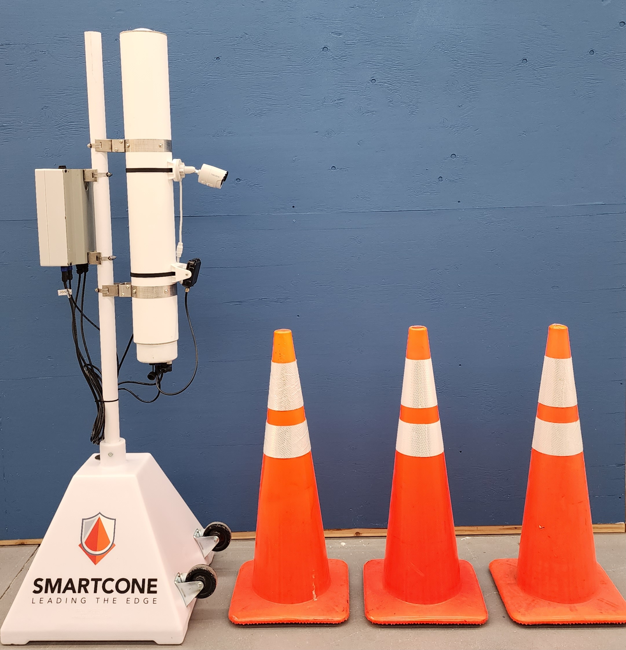 TheSmartCone mobile cart unit, branded base, next to standard traffic cones for scale